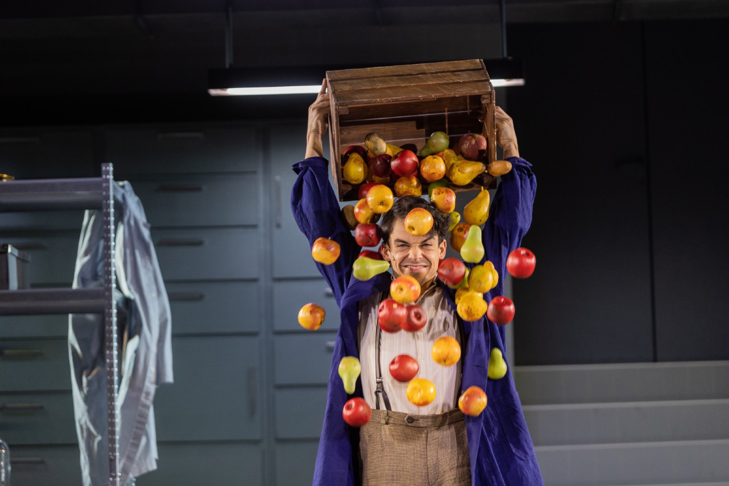 Actor emptying a crate of apples over his head