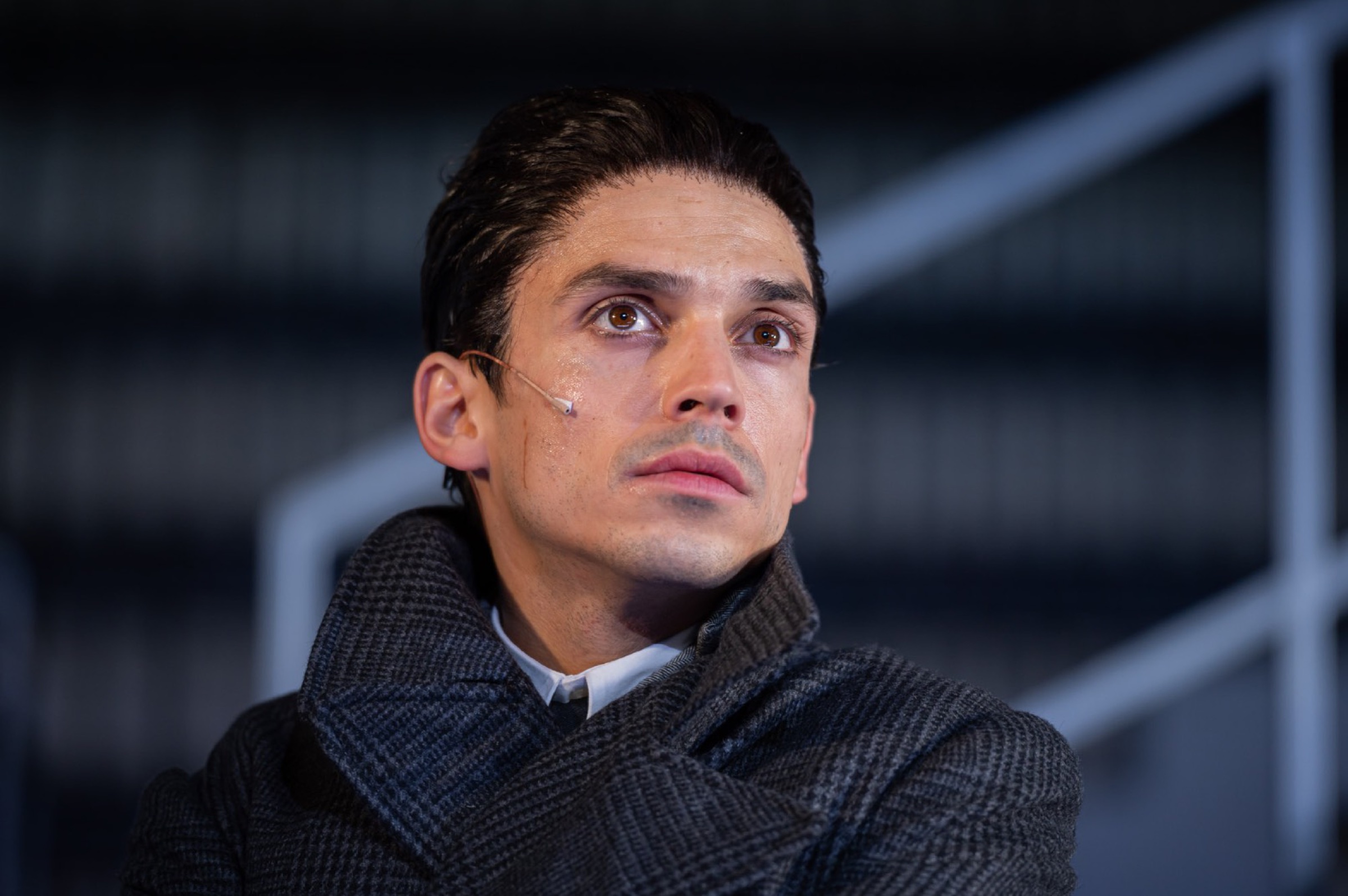 Actor in a grey coat looking up