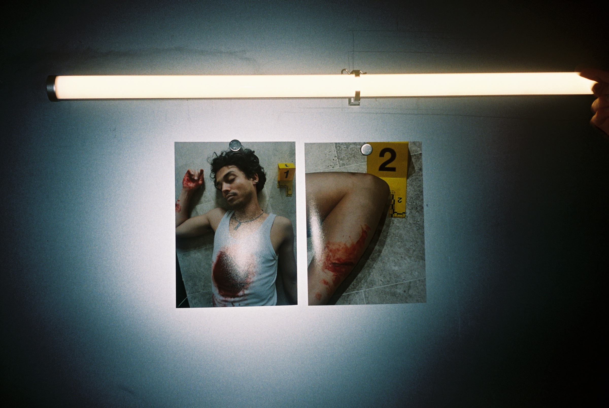 Two photographs taped to a wall under a fluorescent tube
